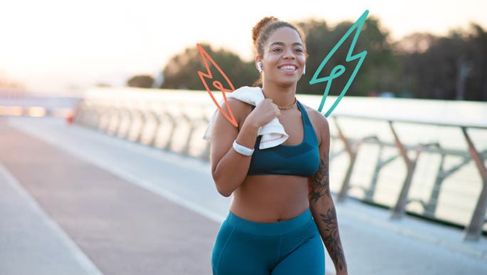 Young woman walking outside in blue activewear carrying a gym towel